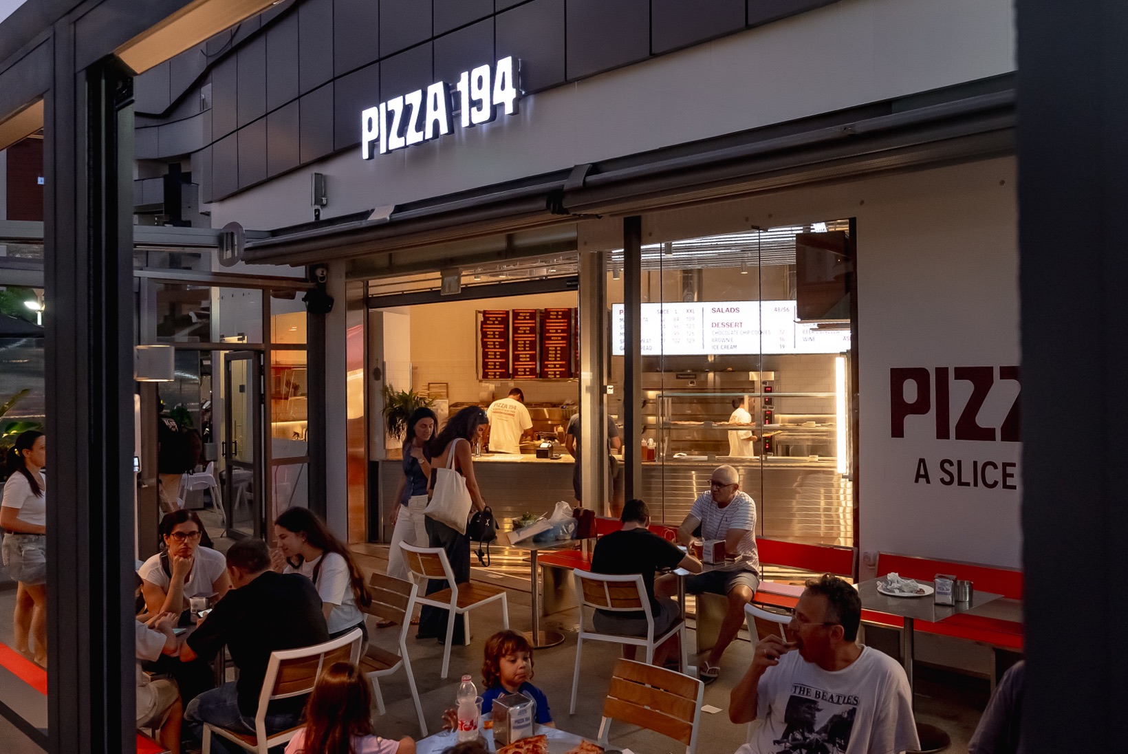 חזית סניף נס ציונה בערב — שלט Pizza 194 מואר וסועדים יושבים בחוץ